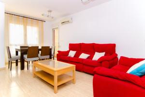 Una sala de estar con un sofá rojo y una mesa. en Apartamento de 4 dormitorios muy céntrico en San Juan Pueblo a tan sólo 2,5 km de la playa de San Juan y Muchavista, en San Juan de Alicante