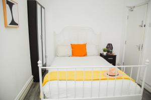 a bedroom with a white bed with an orange pillow at Modern Central Oasis in Liverpool