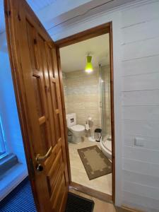 ein Badezimmer mit einem WC und einer Holztür in der Unterkunft RYTO GARSAI in Merkinė