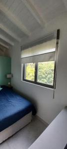 a bedroom with a blue bed and a window at Un cocon les pieds dans l'eau in Le Moule