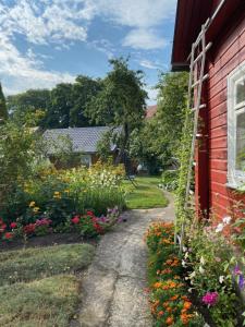 um caminho de jardim ao lado de uma casa vermelha com flores em RYTO GARSAI em Merkinė