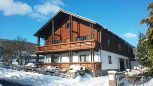 a large wooden house in the snow with snow at Ferienwohnung Rhönblick in Hilders