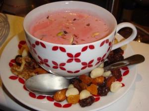 a cup of soup sitting on a plate with food at Taj Mahal Residency Muzaffarabad in Muzaffarabad