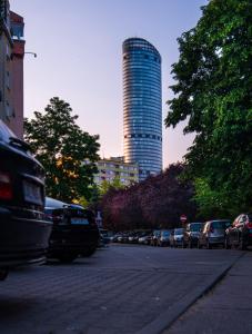 parking z samochodami zaparkowanymi na ulicy z wysokim budynkiem w obiekcie Studio Szczęśliwa 36 przy SkyTower! we Wrocławiu