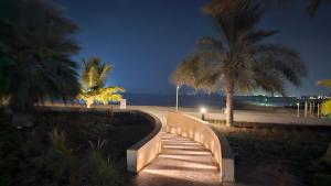 um caminho para a praia à noite com palmeiras em Full Sea view studio em Ras al-Khaimah