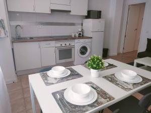 a kitchen with a table with white dishes on it at San Centro Airport IFEMA Wizink Metropolitano Apartments in Madrid