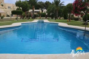 a swimming pool in a resort with blue water at Captivating 2-Bed Beachside Apartment in Mojacar in La Marina de la Torre