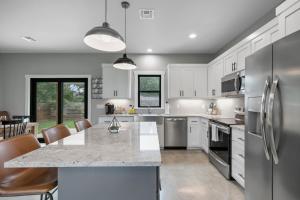 a kitchen with white cabinets and stainless steel appliances at Luxury Home 3blck from Main St with FirePit in Fredericksburg