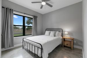 a white bedroom with a bed and a window at Luxury Home 3blck from Main St with FirePit in Fredericksburg