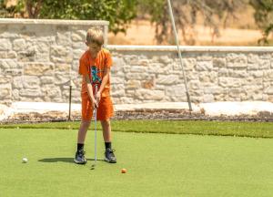 a young boy is playing golf on the grass at Resort at Fredericksburg Unit 1 in Rocky Hill