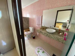 ein rosafarbenes Bad mit einem Waschbecken und einem Spiegel in der Unterkunft CASA DE TEMPORADA MEL in Piranhas