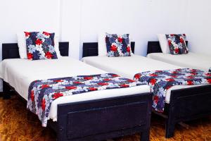 three beds in a room with red and blue quilts at Hotel Sanasuma in Hambantota
