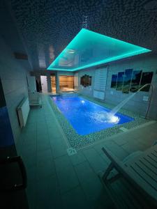 a swimming pool in a building with a blue lighting at HOTEL DaMir in Samarkand