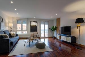 a living room with a blue couch and a tv at Cinco Sentidos by Unique Rooms in Burgos