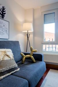 a living room with a blue couch and a lamp at Cinco Sentidos by Unique Rooms in Burgos