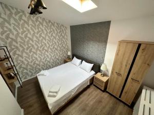 um quarto com uma cama branca e uma parede em XOX Villa House & Garden Bucharest em Bucareste