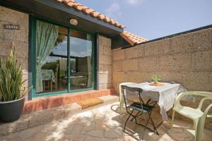 patio con mesa, sillas y ventana en Casa Munay en Granadilla de Abona