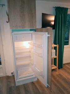 an empty refrigerator with its door open in a room at Cosy et moderne centre ville Gourin in Gourin