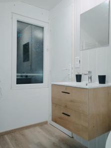 ein weißes Bad mit einem Waschbecken und einem Fenster in der Unterkunft Cosy et moderne centre ville Gourin in Gourin