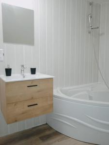 ein weißes Badezimmer mit einer Badewanne, einem Waschbecken und einer Badewanne in der Unterkunft Cosy et moderne centre ville Gourin in Gourin