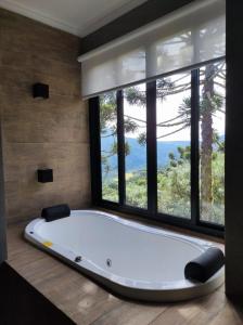 a bath tub in a room with a large window at Chalé Rosa Vermelha in Urubici