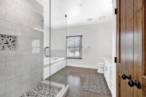 een badkamer met een douche, een bad en een toilet bij Schubert Inn Cottage - Pool - Walk to Main St in Fredericksburg
