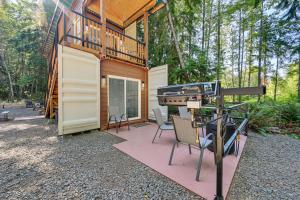 a cabin in the woods with a grill and chairs at Unique Container Studio with Deck and Fire Pit! in Buckley