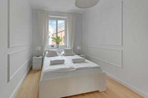 a white bedroom with a large bed and a window at WAVE APARTMENTS WHITE PEARL IN GDANSK in Gdańsk