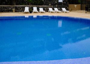 una gran piscina azul con sillones blancos en Villa Del Mar La Tagora costa Adeje panoramic, en Adeje