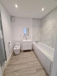 ein Badezimmer mit einer Badewanne, einem WC und einem Waschbecken in der Unterkunft BayVue Apartment & Apartment 7, The Bay House in Shanklin