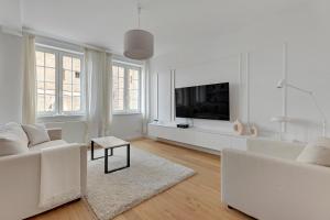 a living room with white furniture and a flat screen tv at WAVE APARTMENTS WHITE PEARL IN GDANSK in Gdańsk