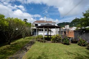 a white house with an umbrella in a yard at Furnas Millhouse in Furnas
