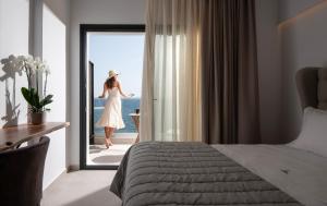a woman in a white dress is looking out the window at G Mare Boutique Hotel in Neos Marmaras