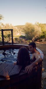 Un uomo e una donna seduti in una vasca idromassaggio di Quinta do Benjamim - Tejo "Experience for 2, family or relax" a Praia do Ribatejo