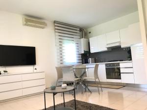 Una cocina con gabinetes blancos y un televisor de pantalla plana. en Casa Céline, en Mestre 2 fotos más