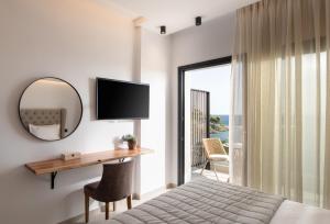 a bedroom with a bed and a desk and a mirror at G Mare Boutique Hotel in Neos Marmaras