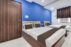 two beds in a room with blue walls at Collection O Hotel Miraaz in Gwalior