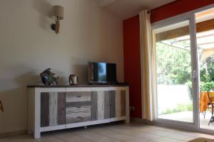 a room with a tv on a dresser with a sliding glass door at CASA PALOMBAGGIA - Piscine Chauffée in Porto-Vecchio