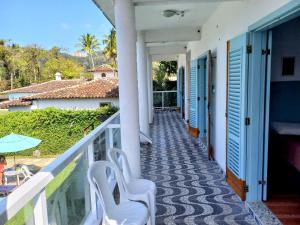 a balcony of a house with blue doors and white chairs at Pousada Eldorado Guarujá - in Guarujá