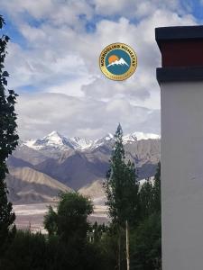 a sign for a building with mountains in the background at Norbooling HomeStay, Leh Ladakh in Leh