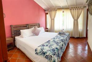 a bedroom with a large white bed with pink walls at Hotel Campestre La Trinidad in San Gil