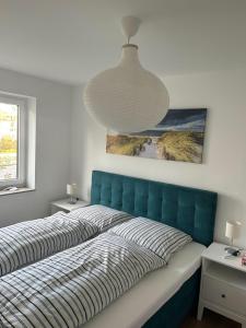 Bett mit blauem Kopfteil in einem Schlafzimmer in der Unterkunft Residenz an der Ostsee in Scharbeutz
