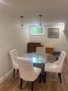 a dining room with a glass table and white chairs at Centre Gate House Licence# 117-2023 in Niagara-on-the-Lake