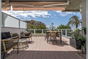 un patio con tavolo e sedie sul balcone. di Suite Homes Hesperides garden beach a Málaga
