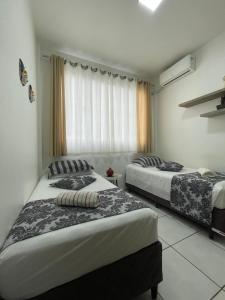 1 dormitorio con 2 camas y ventana en Apto Master de 2 quartos a 100m do Mar, central, en Balneário Camboriú