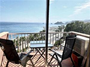 balcón con mesa, sillas y vistas al océano en Estudio Urbanización Las Góndolas, en Almuñécar
