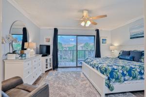 a bedroom with a bed and a tv and a balcony at Modern oceanfront condo with two pools & private washer/dryer in Saint Augustine +36 photos