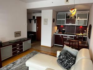 a living room with a white couch and a kitchen at APARTAMENT 345 w Domu Zdrojowym - Jastarnia in Jastarnia