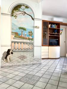 een hond die op de vloer in een keuken zit met een muurschildering bij Lulù Holiday House in Vietri
