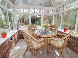 a conservatory with a table and chairs and windows at The Old Barn in Mold